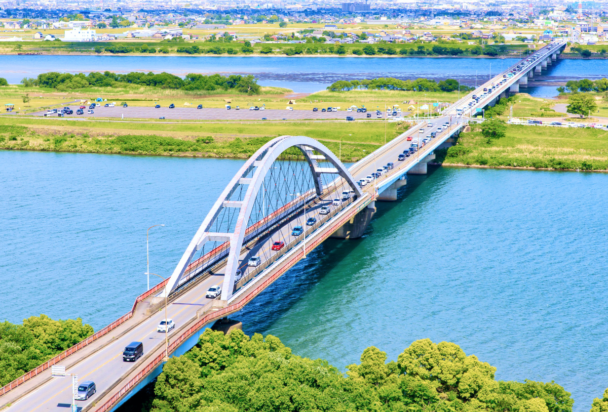 アーチ型の橋が川を渡り、多くの車が橋を走行している風景。